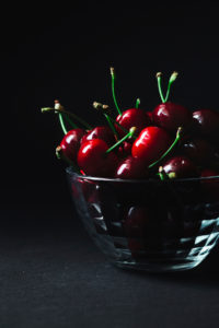 A glass bowl filled with fresh cherries