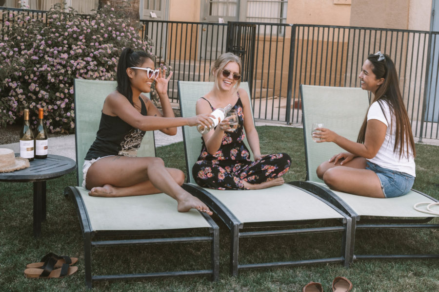 Three ladies enjoying wine on outdoor poolside lounge chairs