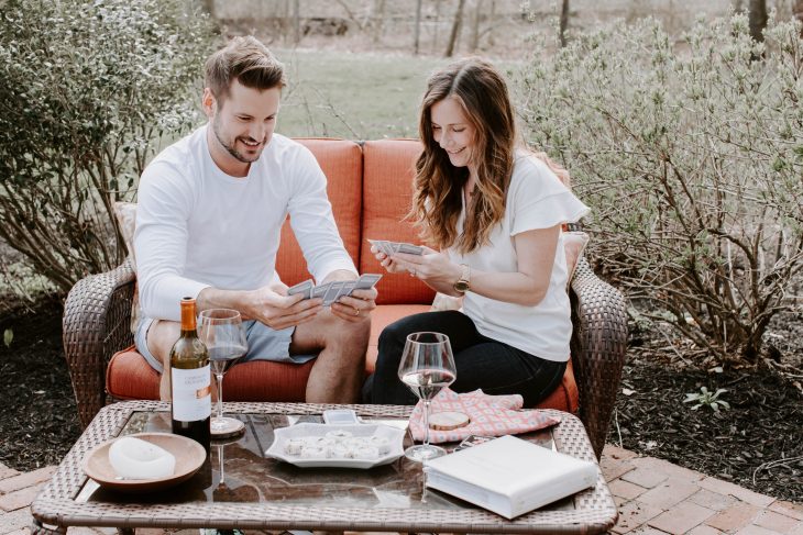 Couple playing cards while enjoying wine and snacks outside