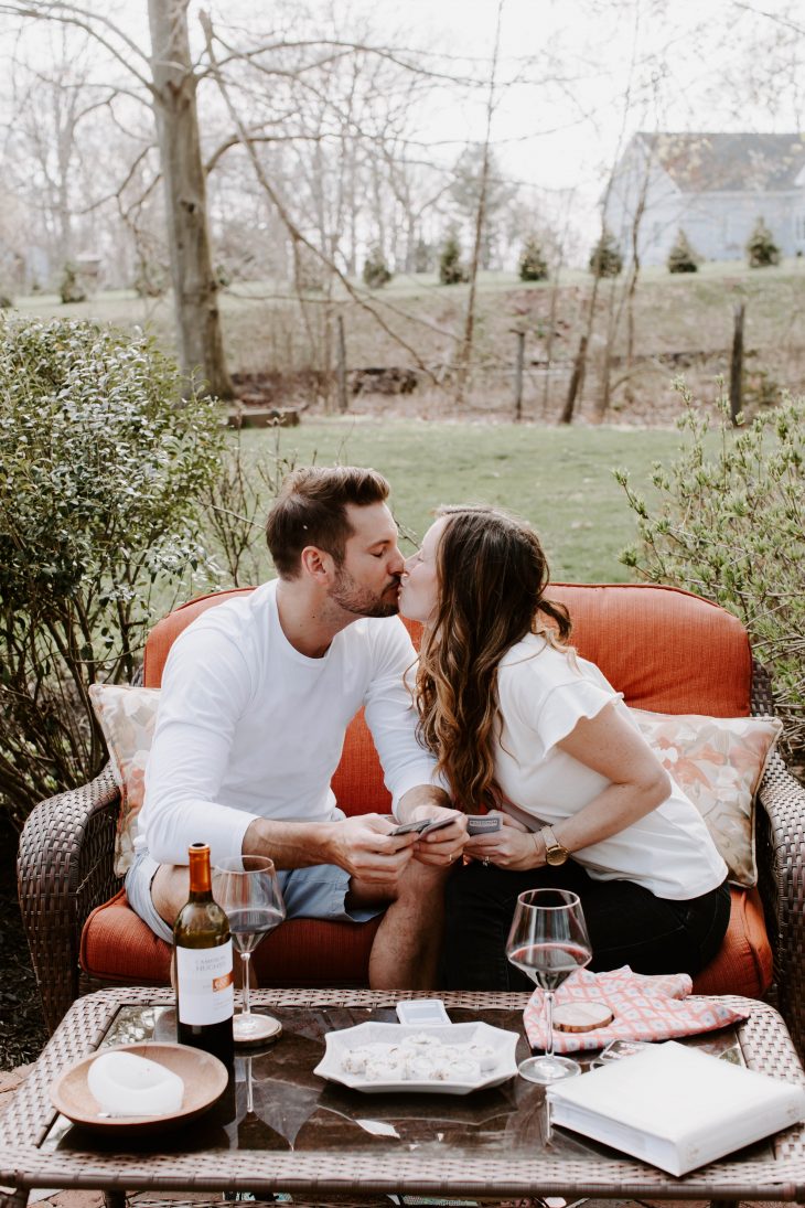 A couple kissing while enjoying wine with a card game