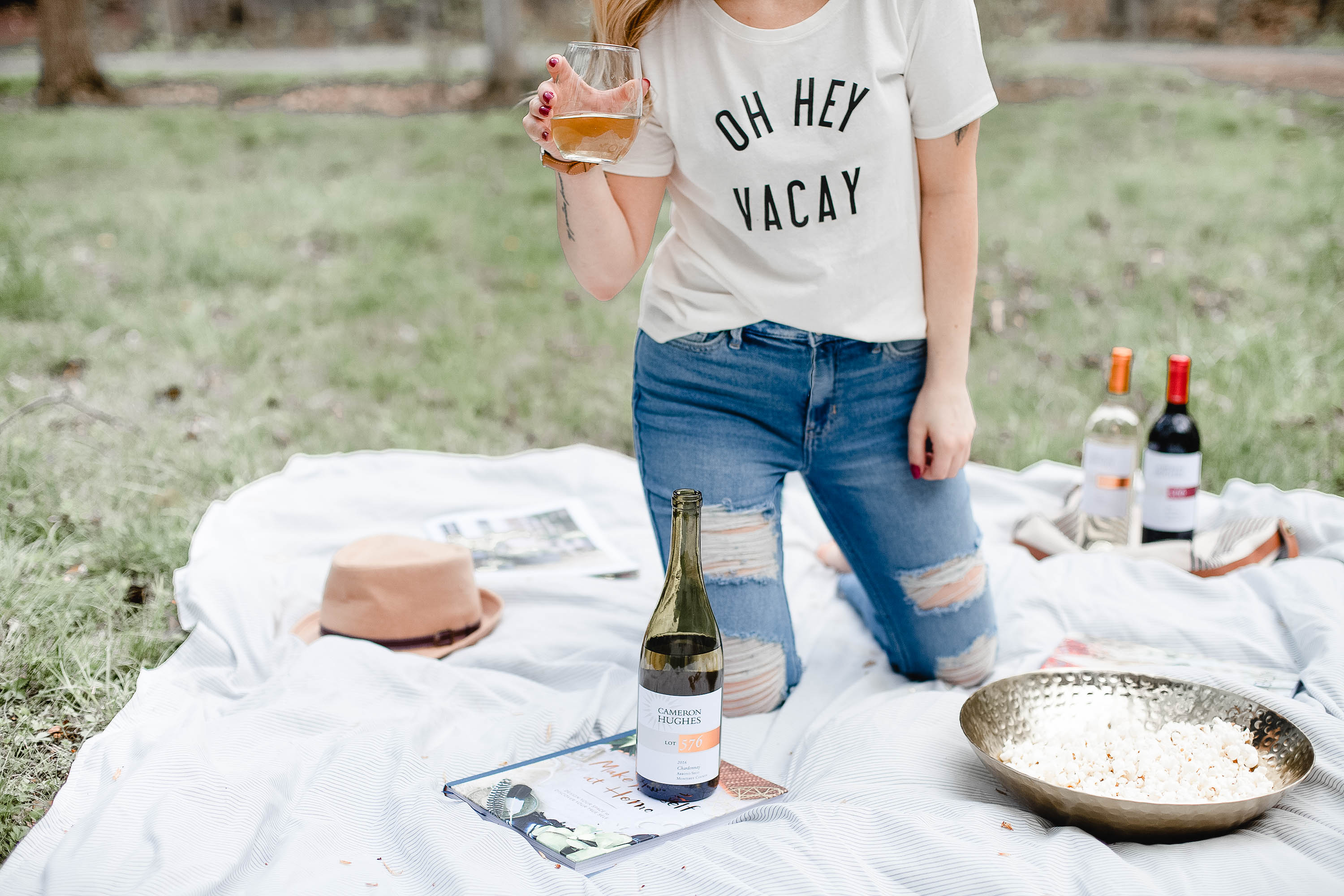 Girl on picnic blanket with Rose wine and Oh Hey Vacay T-Shirt