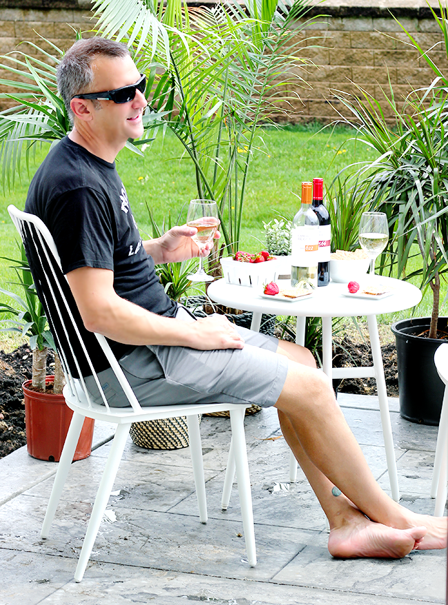 Men enjoying a glass of white wine on a porch picnic table