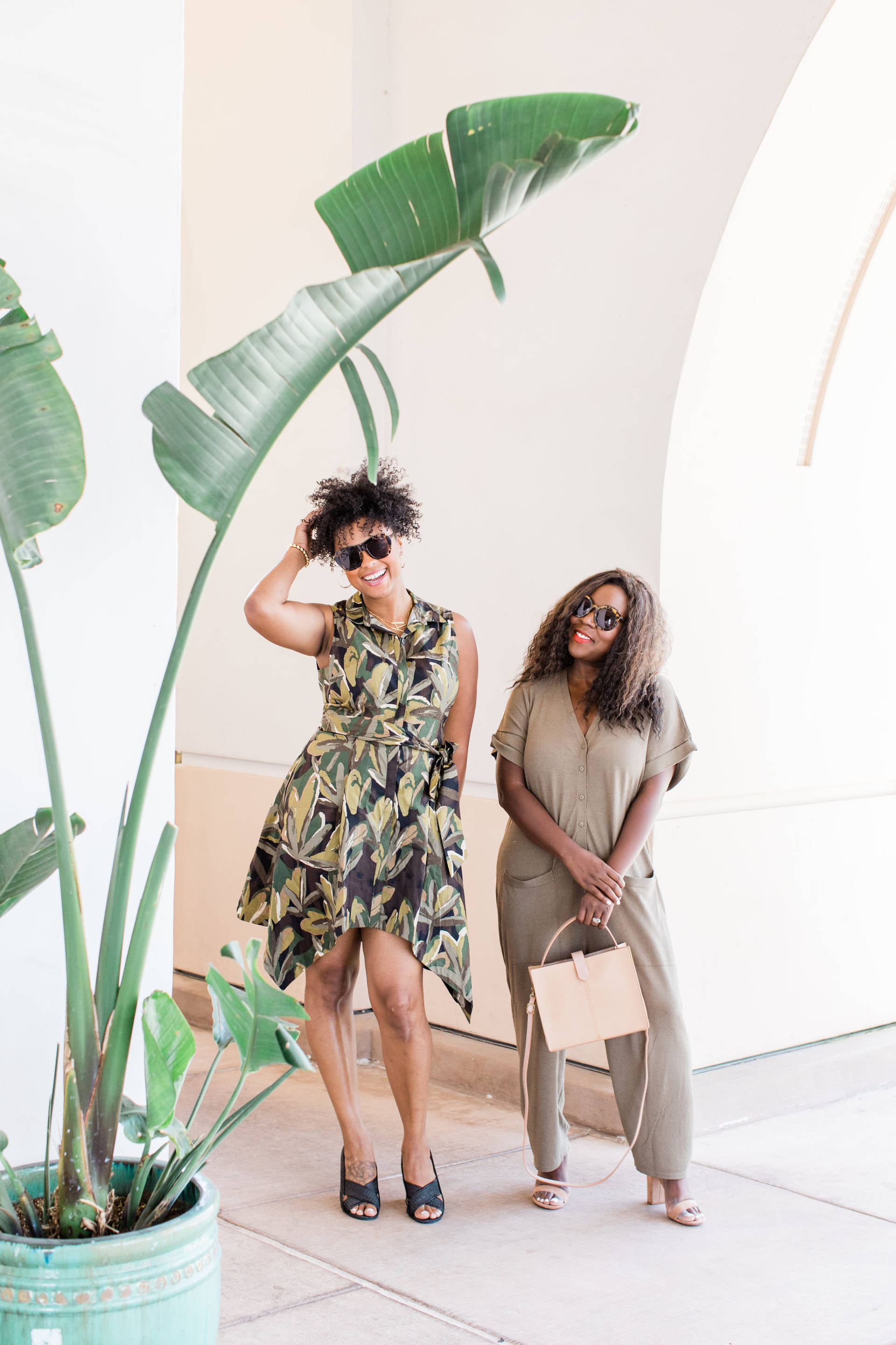 Two women dressed beautifully under an indoor palm tree