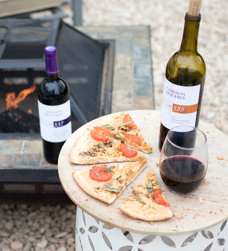 Vegan caprese pizza slices next to a poured glass of Cameron Hughes Lot 588 wine