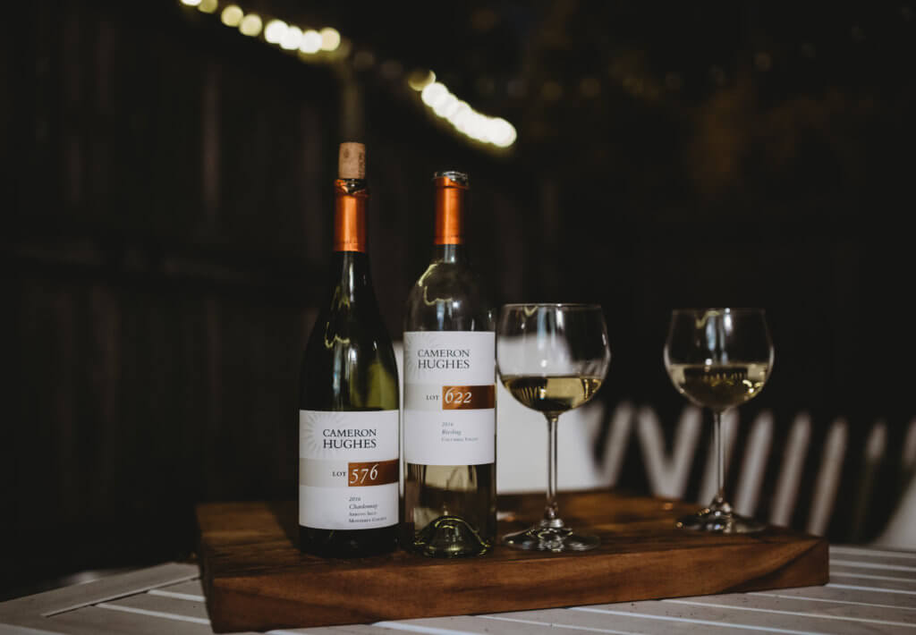 Two bottles and poured glass of Cameron Hughes Wine white wines