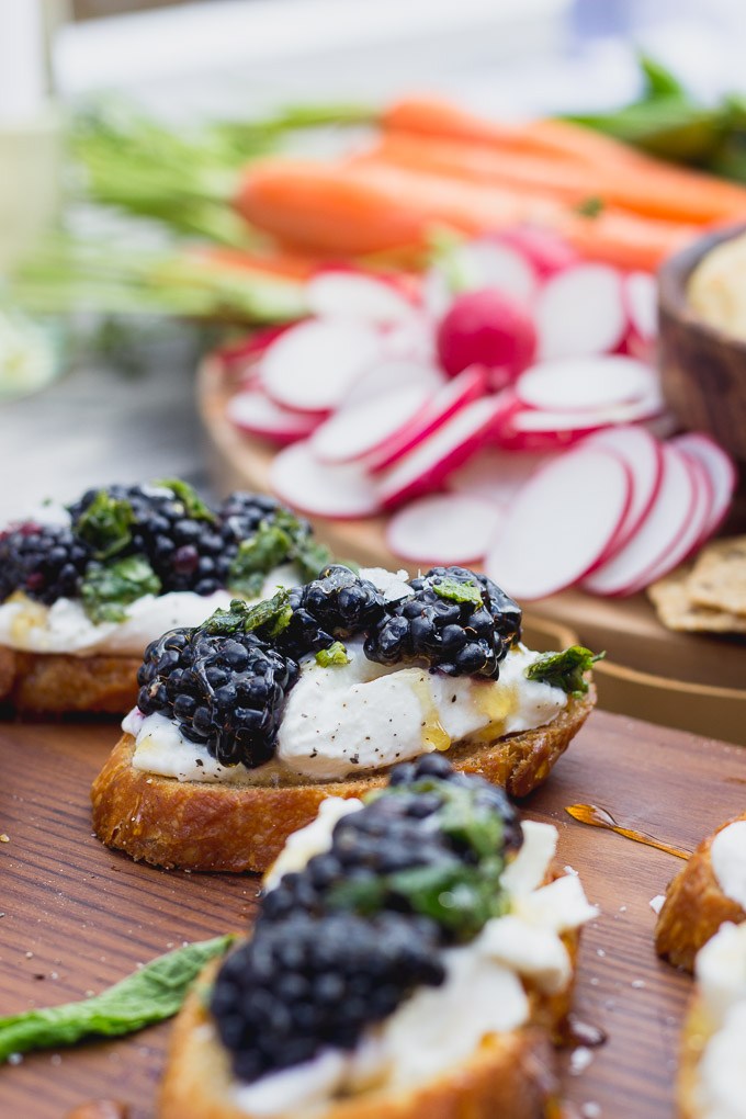 Blackberry Burrata Mint Crostini with a veggie tray in the background