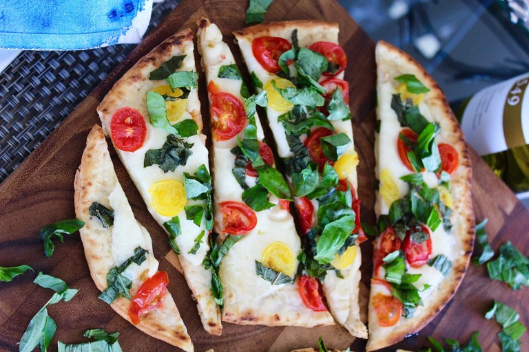 Flatbreat pizza with a bottle of wine and fresh basil