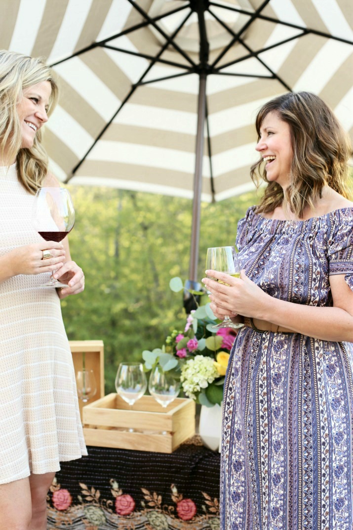Two women enjoying wine under an outdoor umbrella