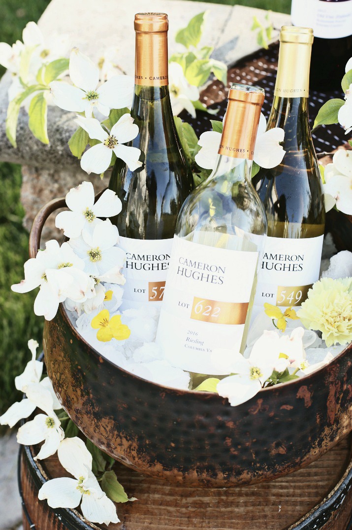 Three bottles of Cameron Hughes wine in a basket with flowers
