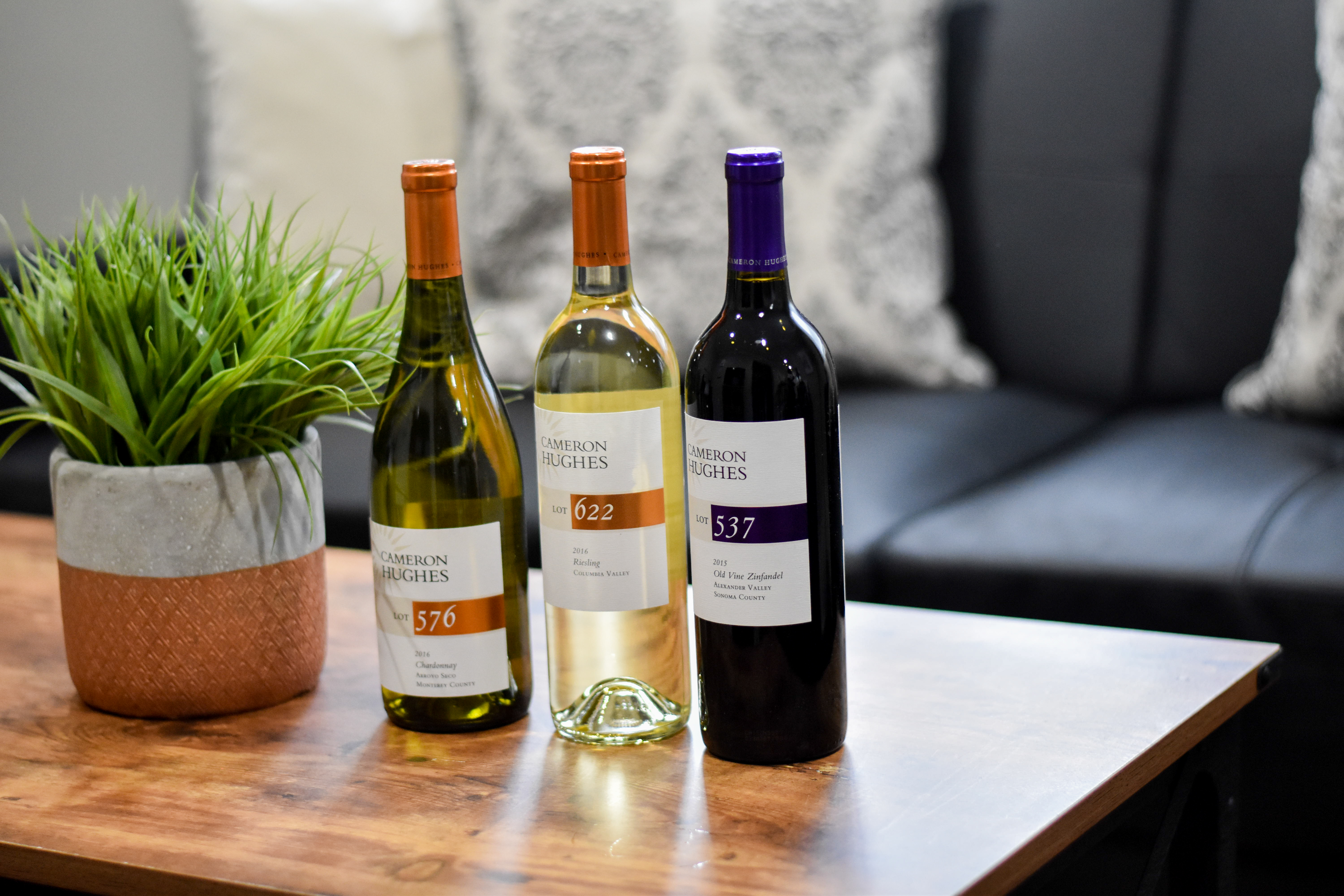 Three bottles of Cameron Hughes wine on a wood table