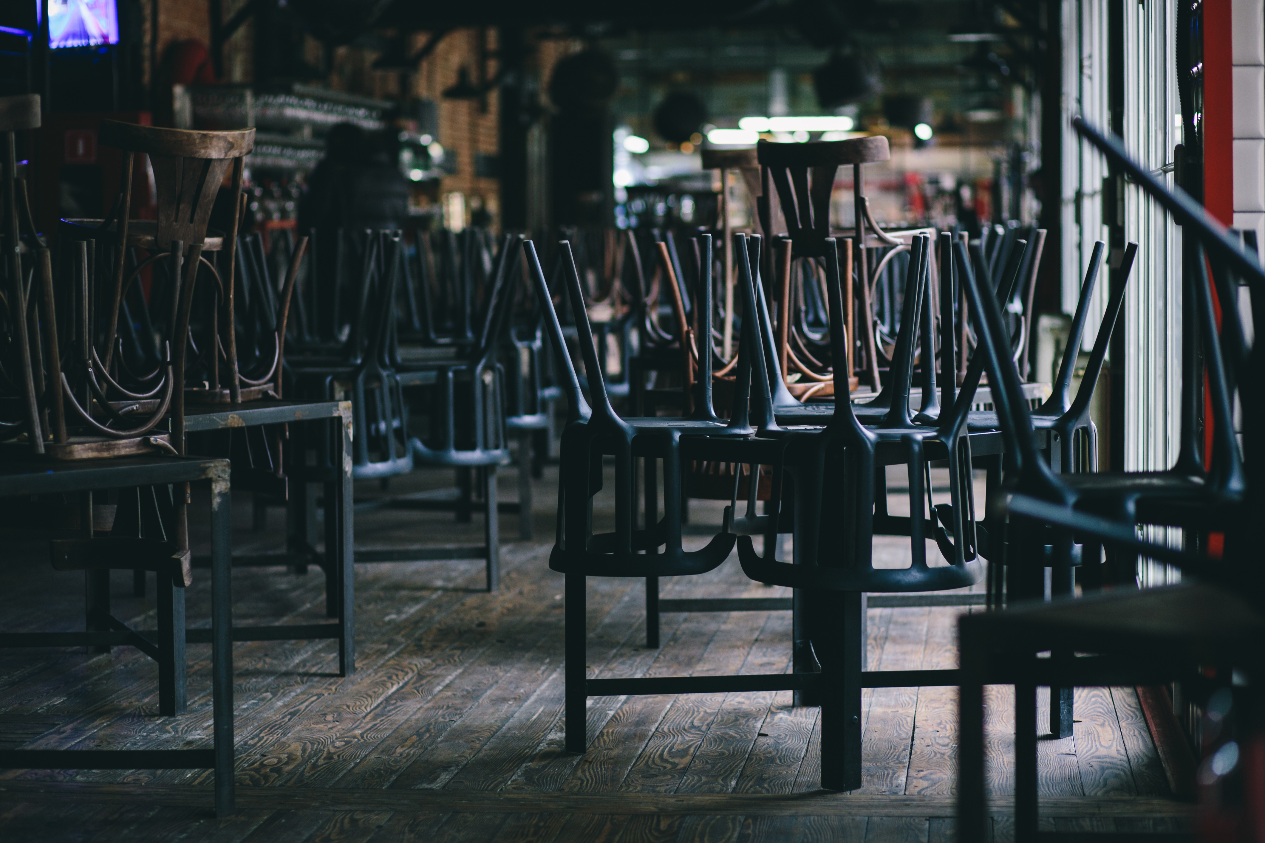 Chairs stacked on tables in a dark restaurant that is closed