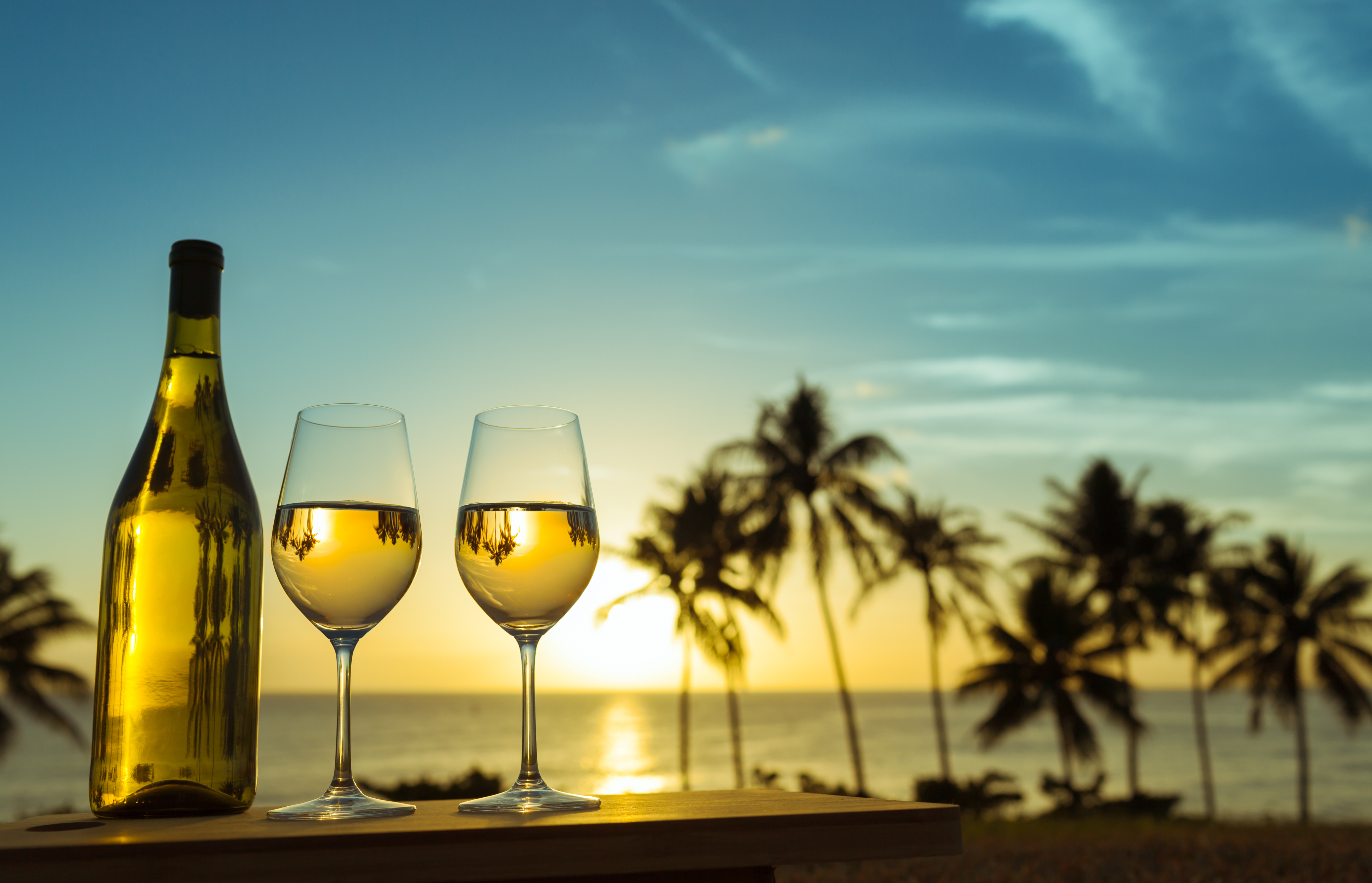 Hawaiian white wine bottle and glasses with palm trees and sunset