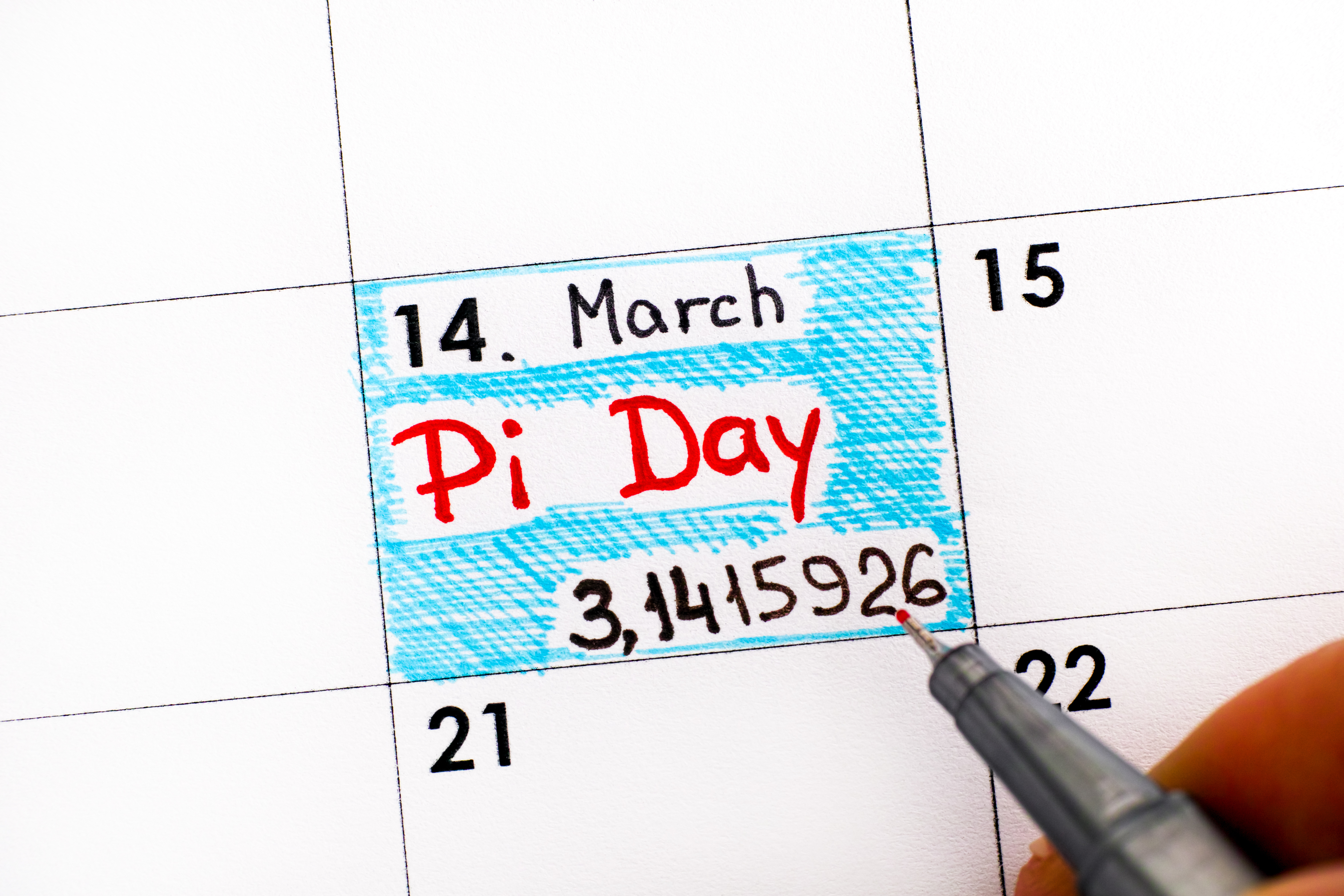 Woman fingers with pen writing reminder Pi Day in calendar. Pi Day is celebrated on March 14th around the world.