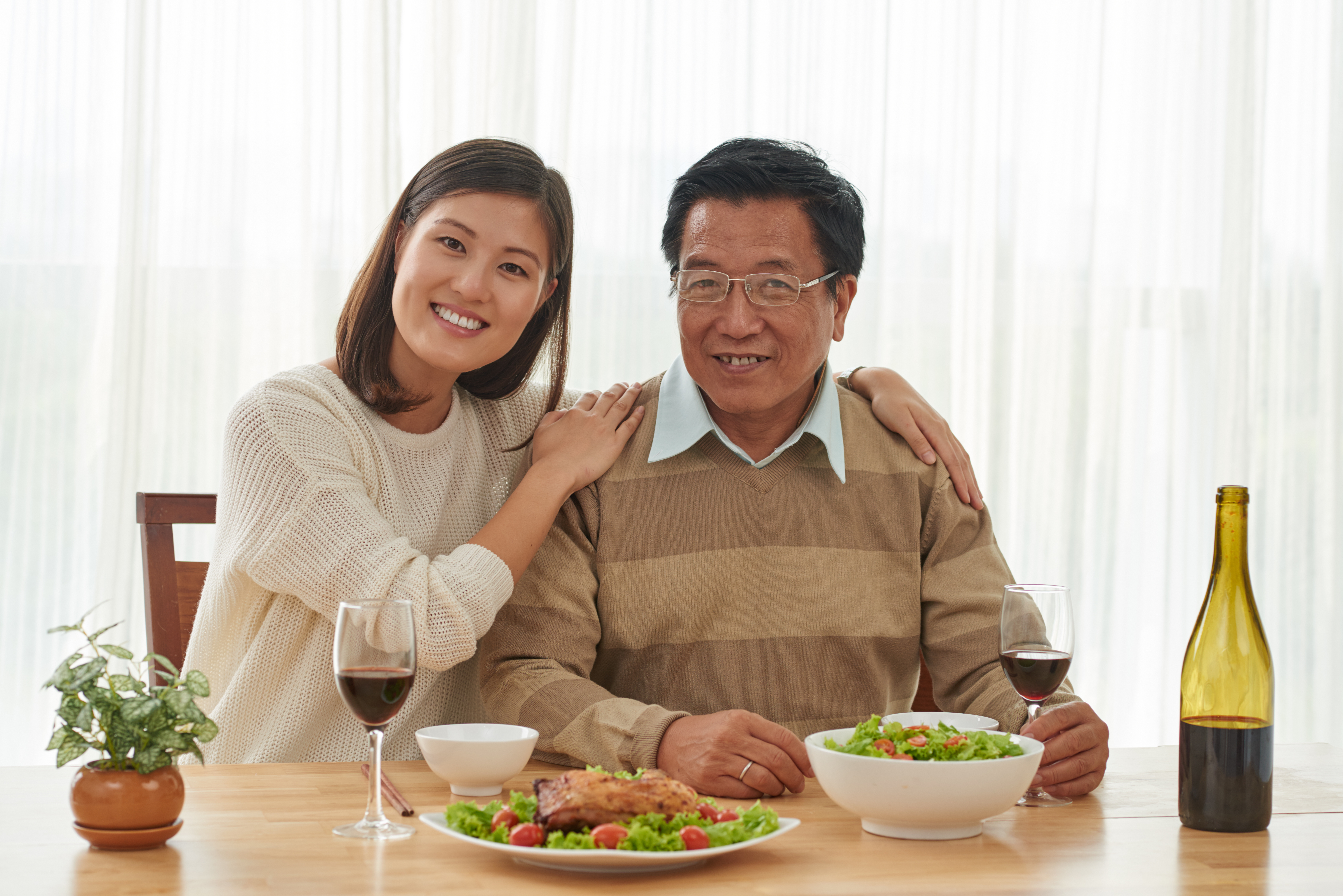 Portrait of happy Vietnamese father and his adult daughter having dinner at home