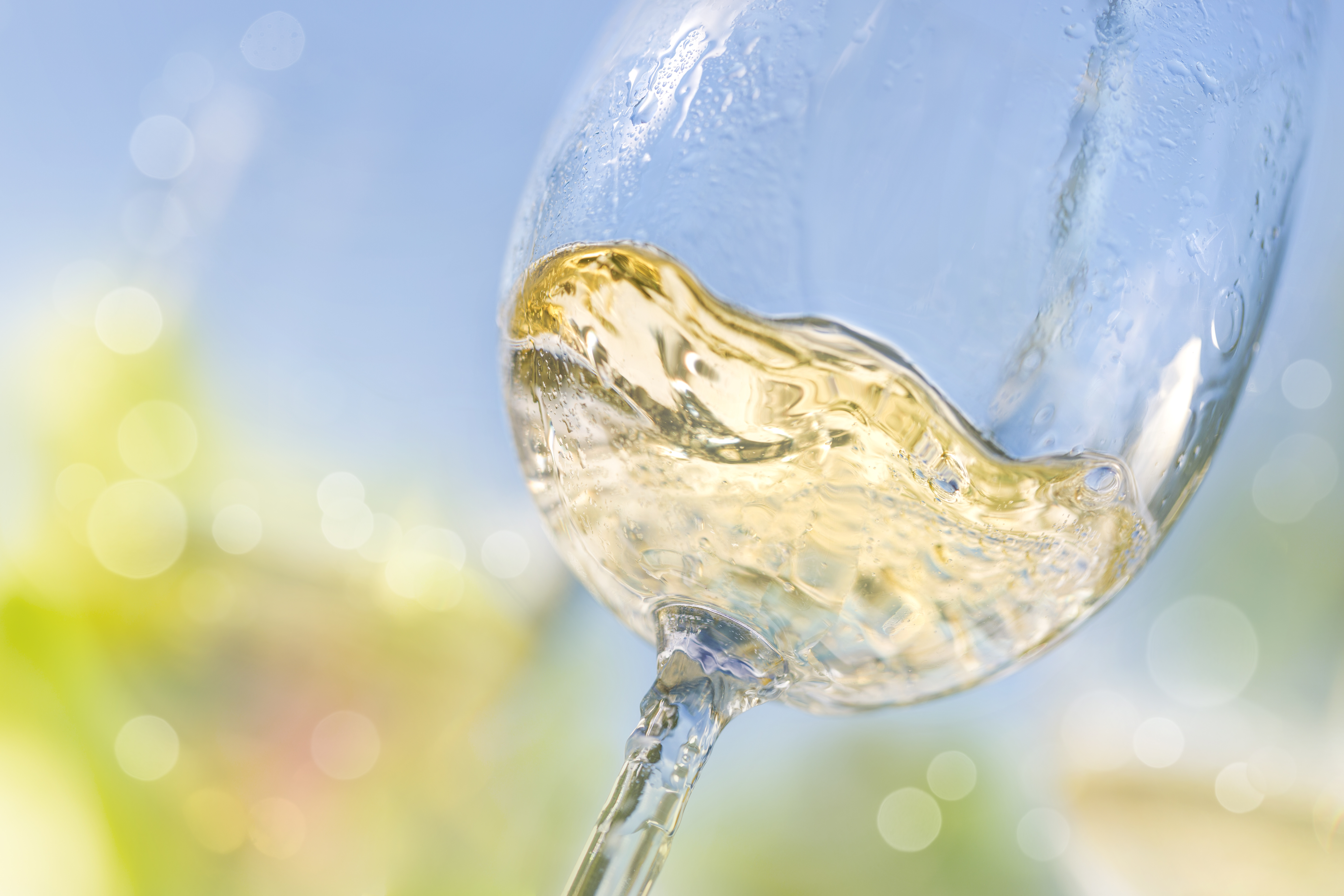 Close up of pouring white wine in a glass and swirling