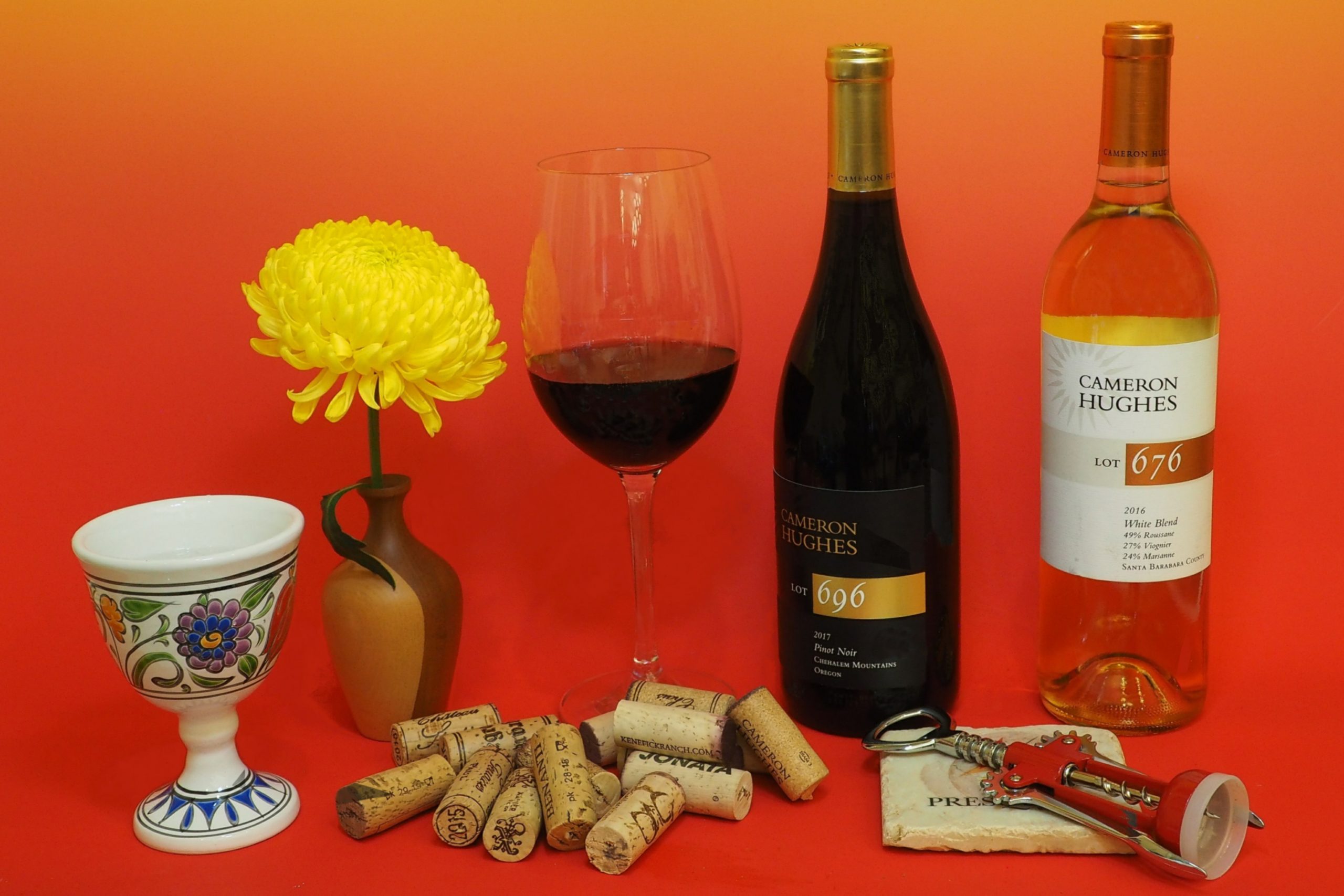 Cameron Hughes Lot 696 and 676 wine bottles with corks, a fresh flower and various wine accessories