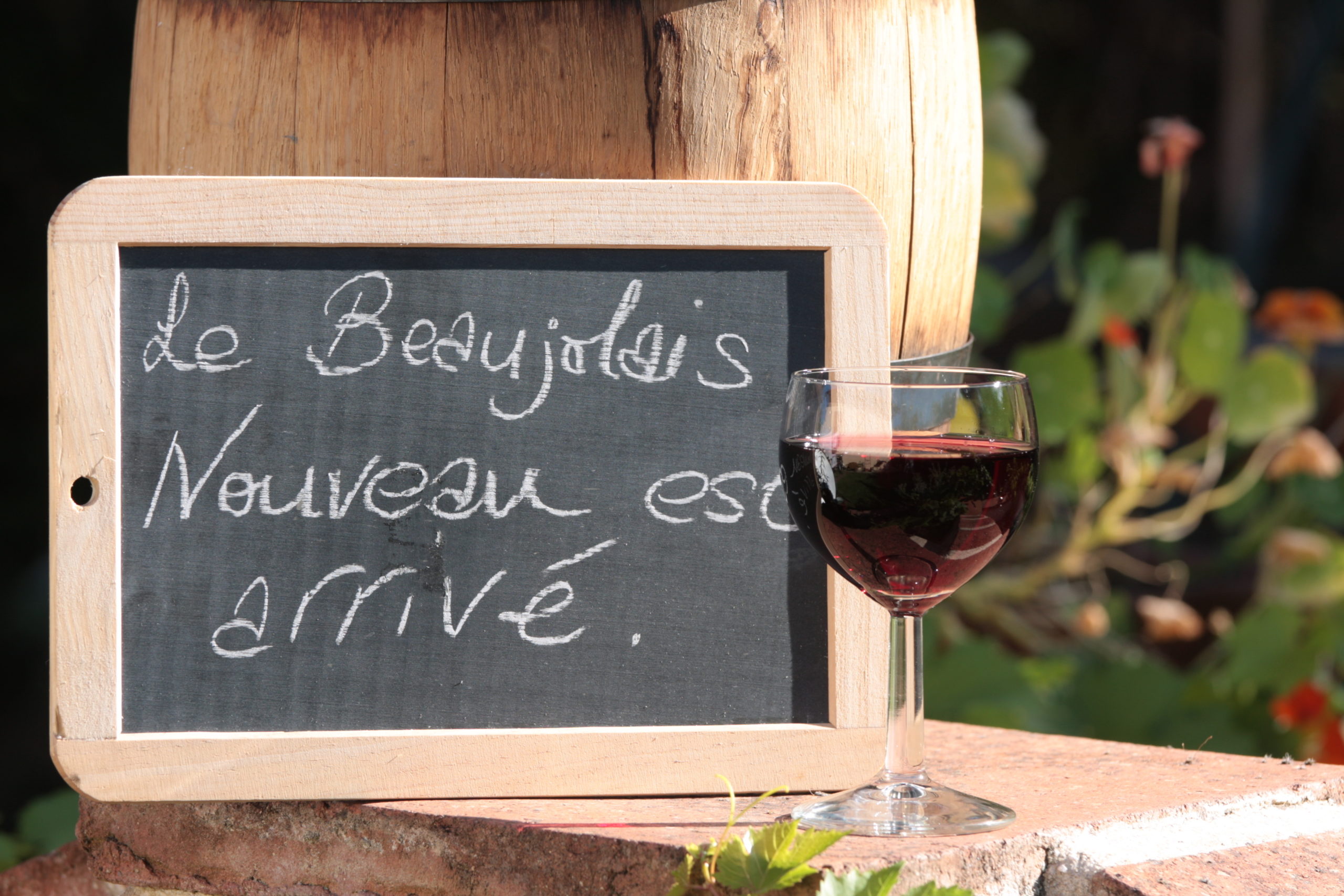 Wine glass and chalkboard sign reading Le Beaujolais Nouveau est arrive