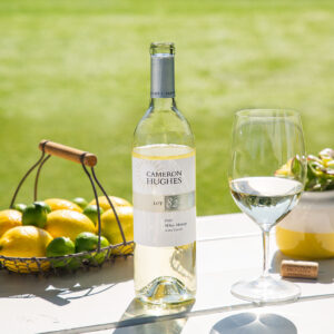 Lot 825 2020 Napa Valley White Meritage outside with a glass poured and fresh lemons and limes